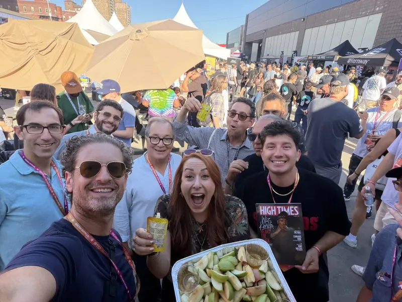 Jordan Isenstadt taking a group selfie with friends and a tray of apple slices at Revelry