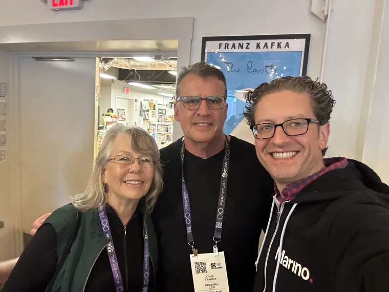 Jordan Isenstadt with two guests in conference lanyards beside a Franz Kafka poster