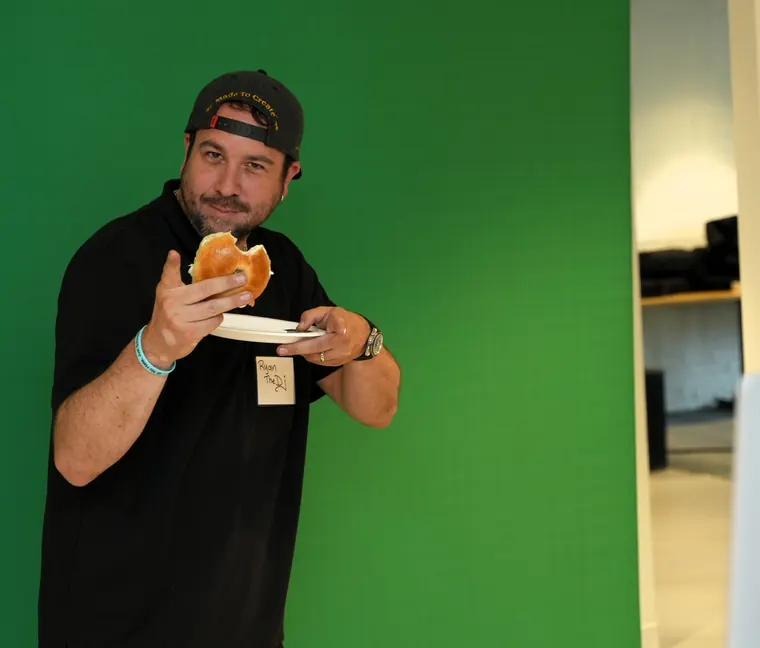 Guest taking a bite of a bagel in front of a green screen