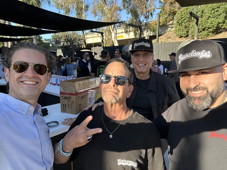 Jordan Isenstadt with three guests in caps by the patio tables