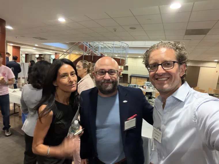 Jordan Isenstadt with three attendees in front of the exhibitor tables in Melville
