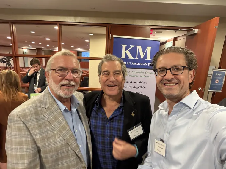Jordan Isenstadt with two guests in front of a law firm banner